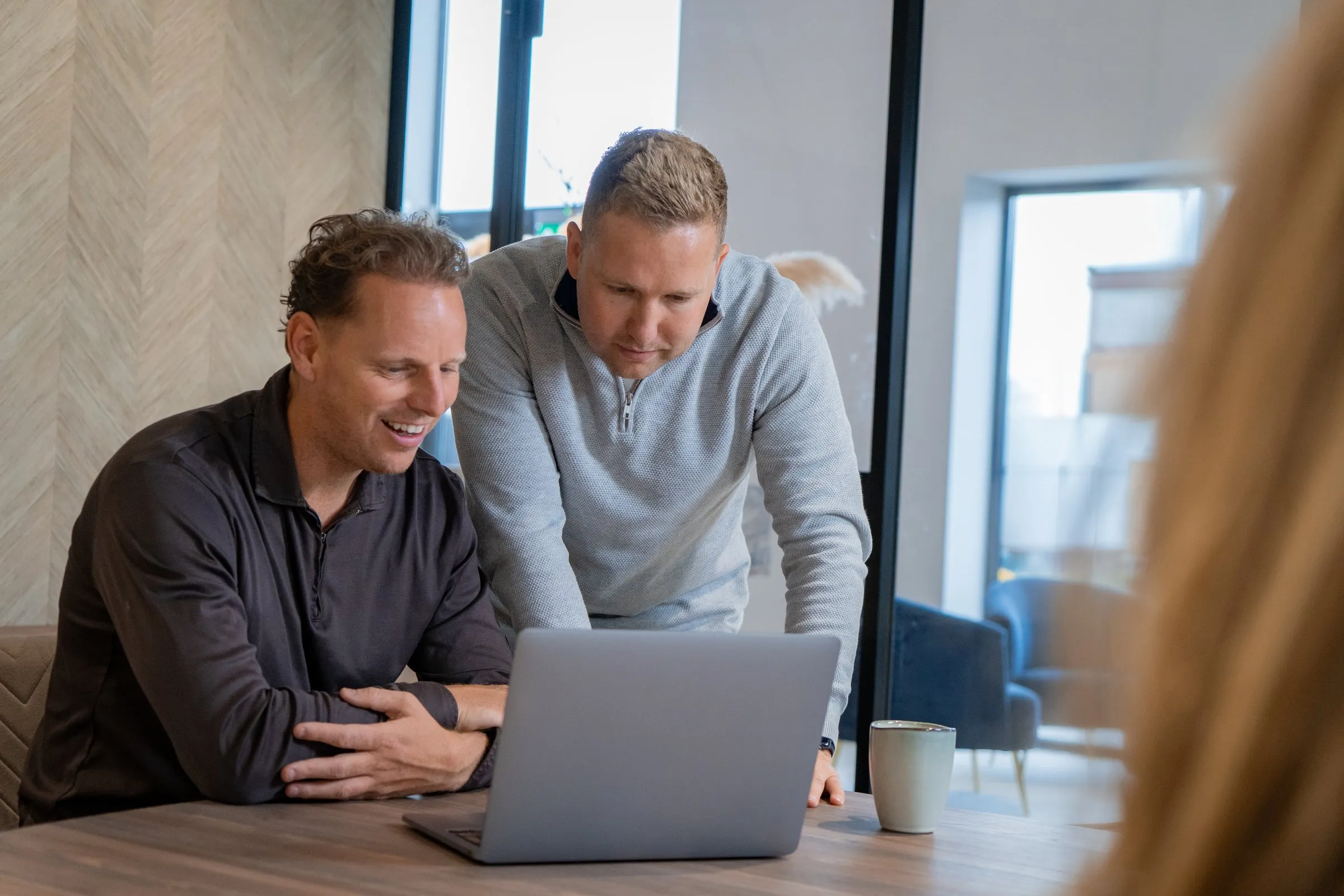 Daan en Tim werken samen aan een laptop op kantoor